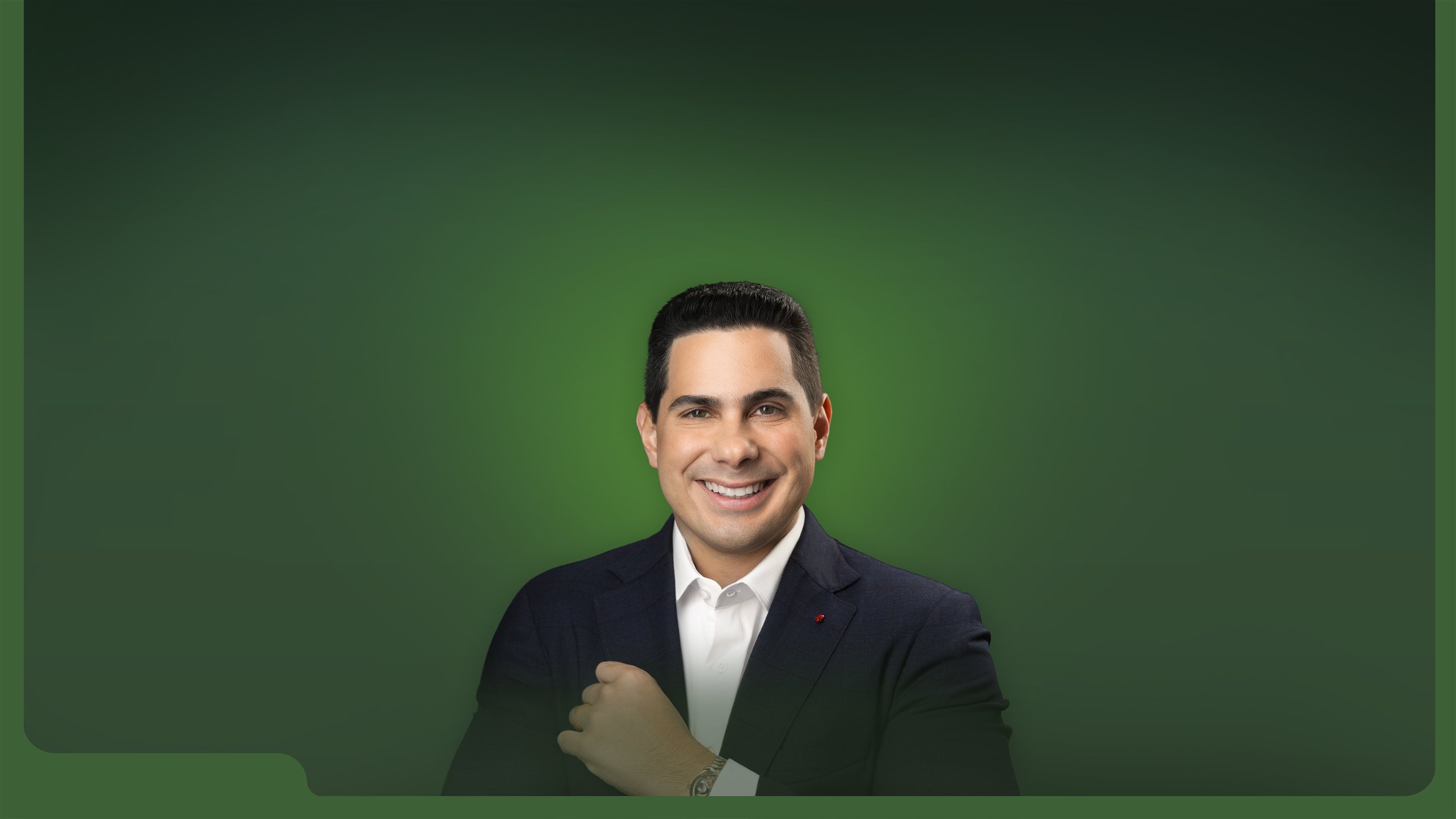 Nilio Portella sorrindo sobre fundo verde.